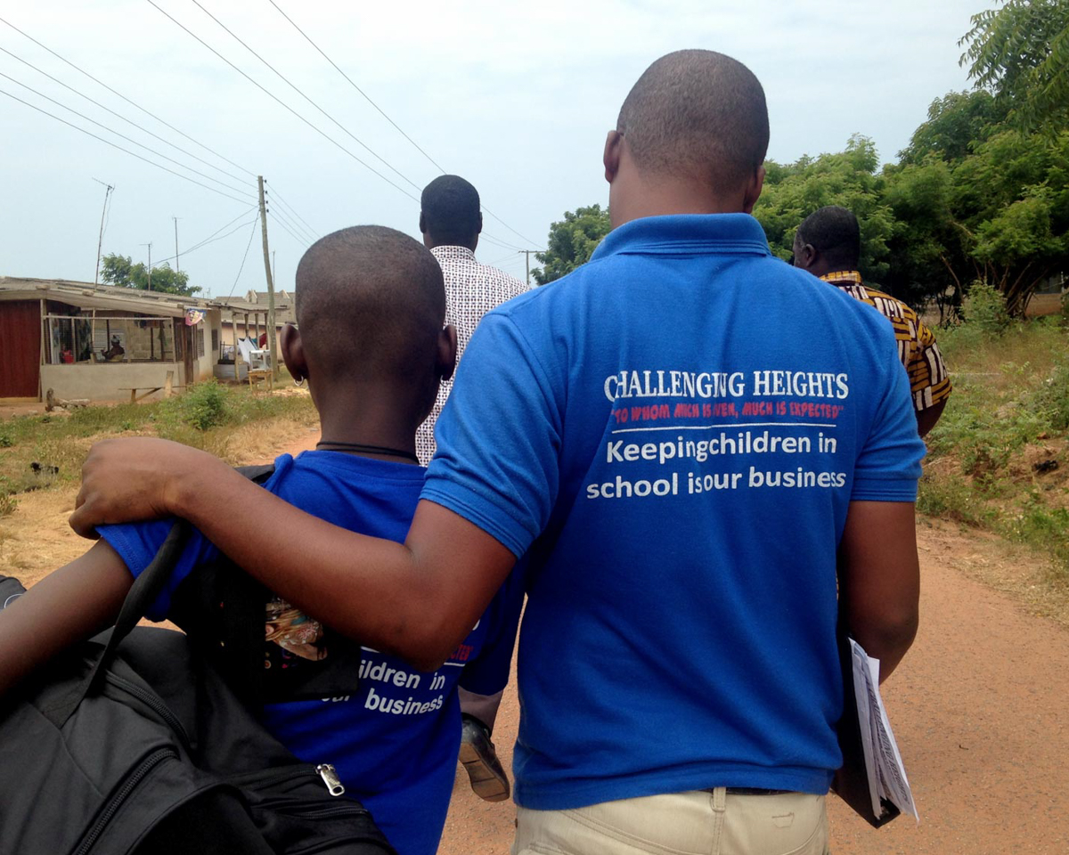 Young Kojo, now free from forced labor, walks away from the camera with a worker from Challenging Heights in Ghana.