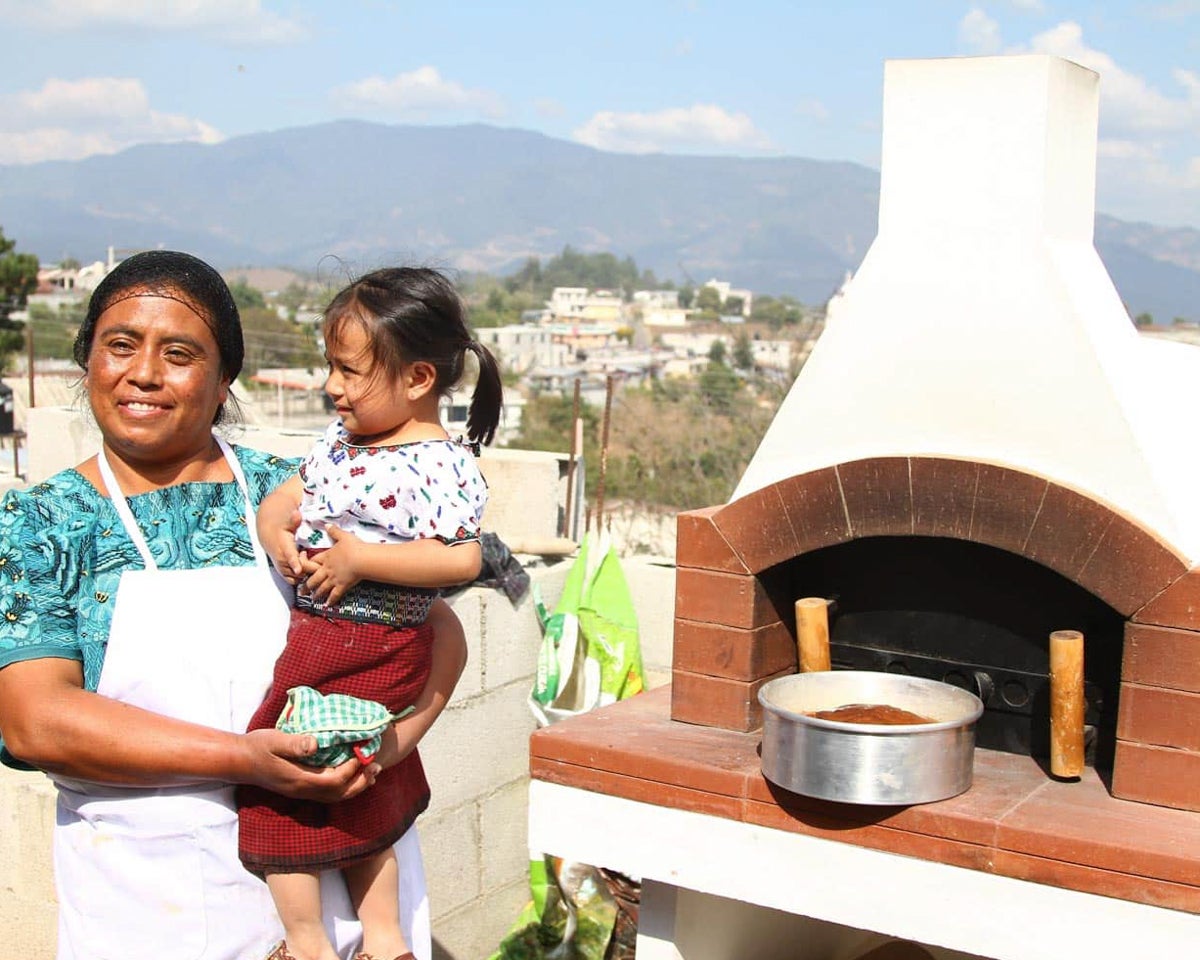 Miriam stands with her daughter in front of the oven that kick-started her baking business.