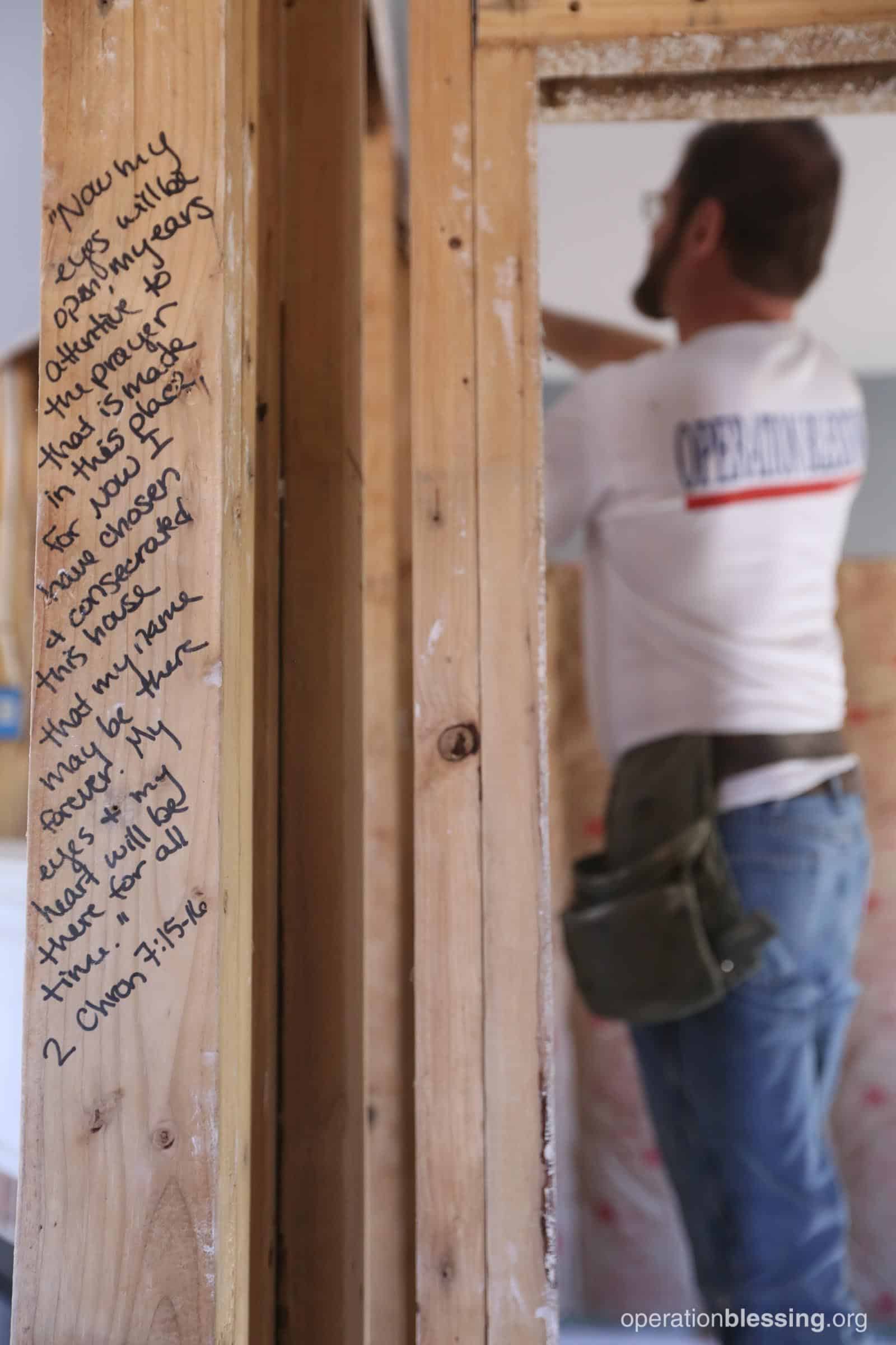 A Bible verse written on the beams as a volunteer works on Winderful’s house.