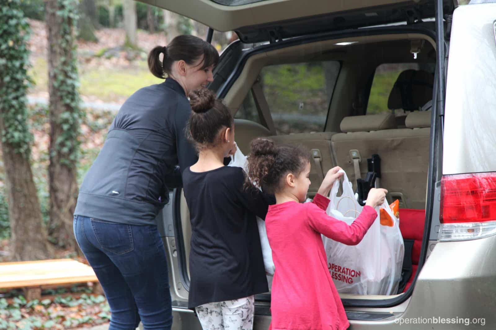 Lakashah and her daughters fill the trunk with free groceries.