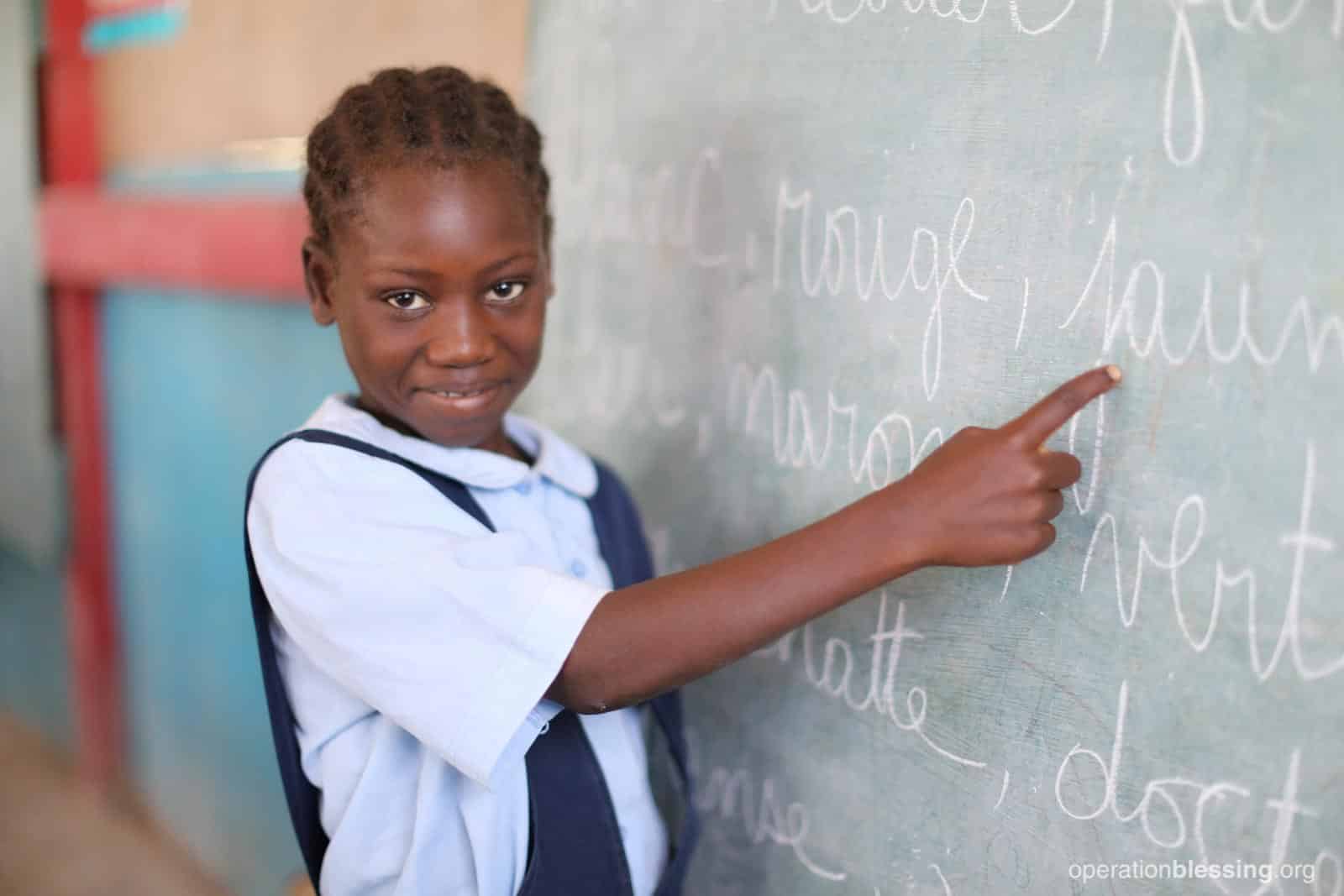 Daphkaline points at the chalkboard. This promising student received a scholarship to continue her education.