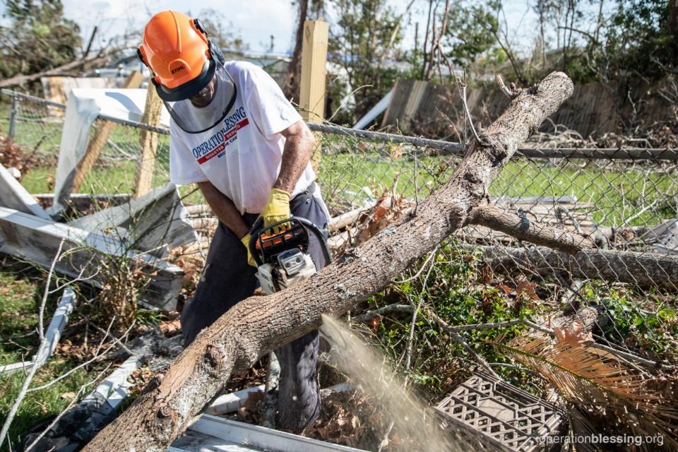 An OBI volunteer chopping fallen trees in Ed’s yard.