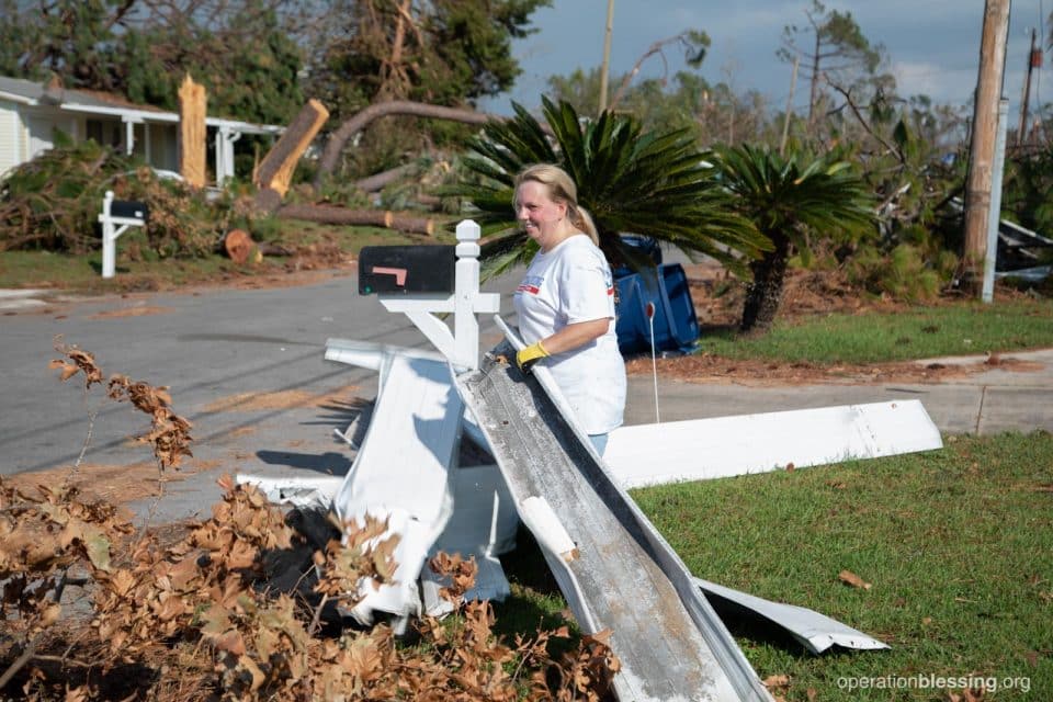 A female volunteer carries debris to the street. 