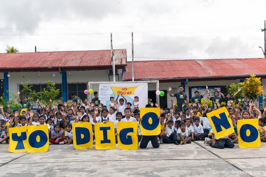 Children in Latin America hold up signs as they learn to say no to child abuse and human trafficking.