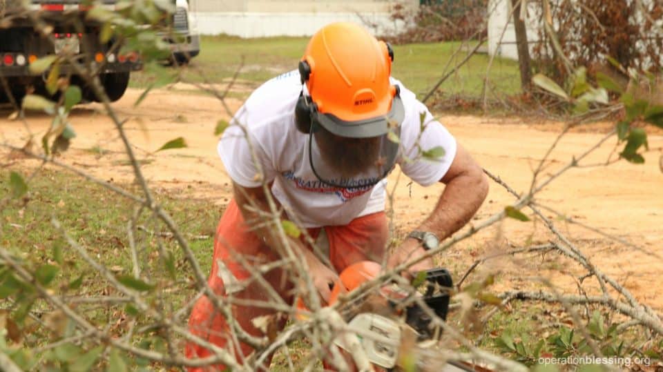 A volunteer using a chain saw on Gene and Marie’s property.