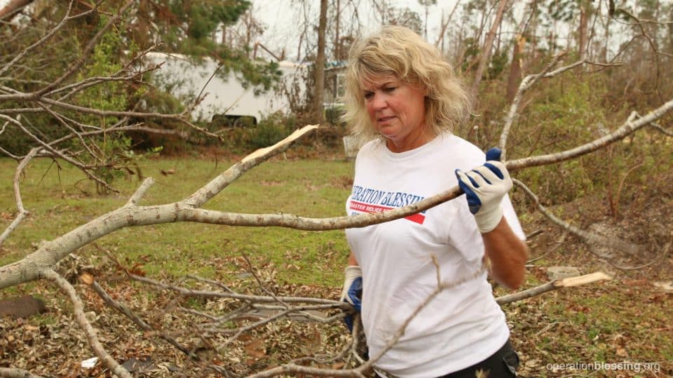 A female volunteer helps clear branches.