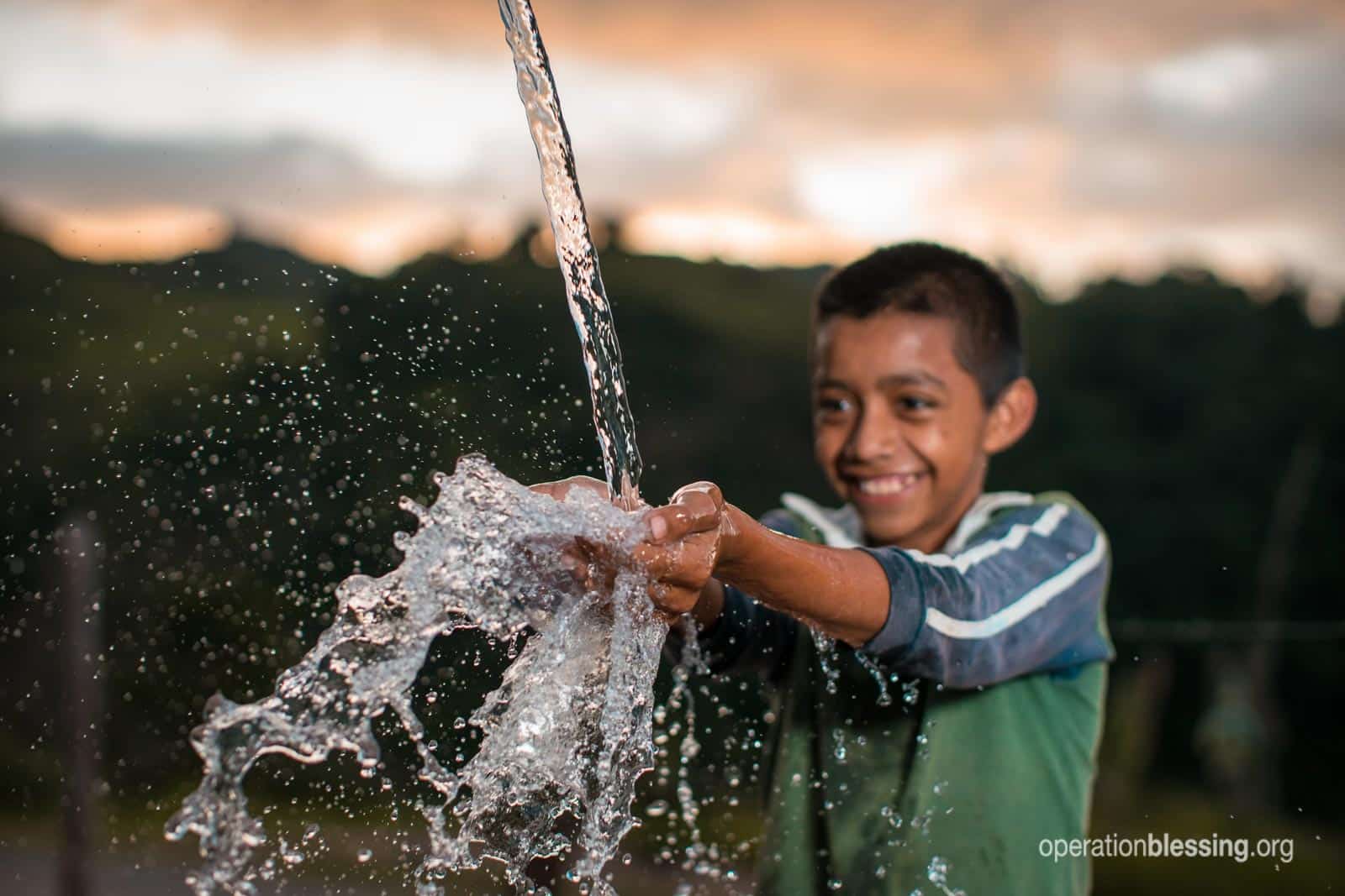 A boy splashing in fresh, clean water.