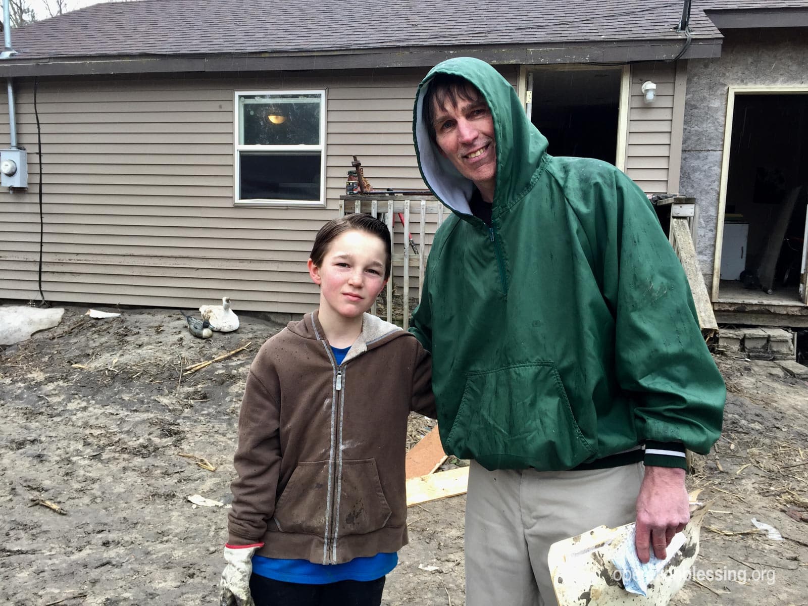 Jack and his son, TJ, stand in front of their flooded home in Nebraska.