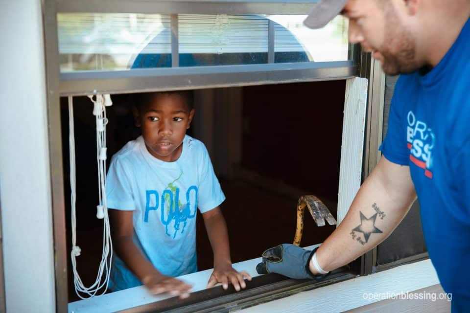 Debra's grandson Christian looks out the window of his flooded home.