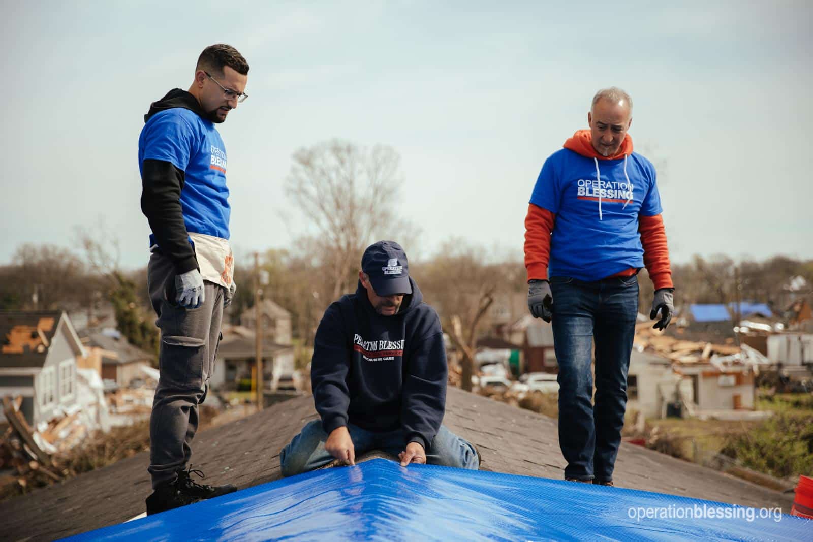 Operation Blessing staff and volunteers tarping Patrice's damaged roof. 