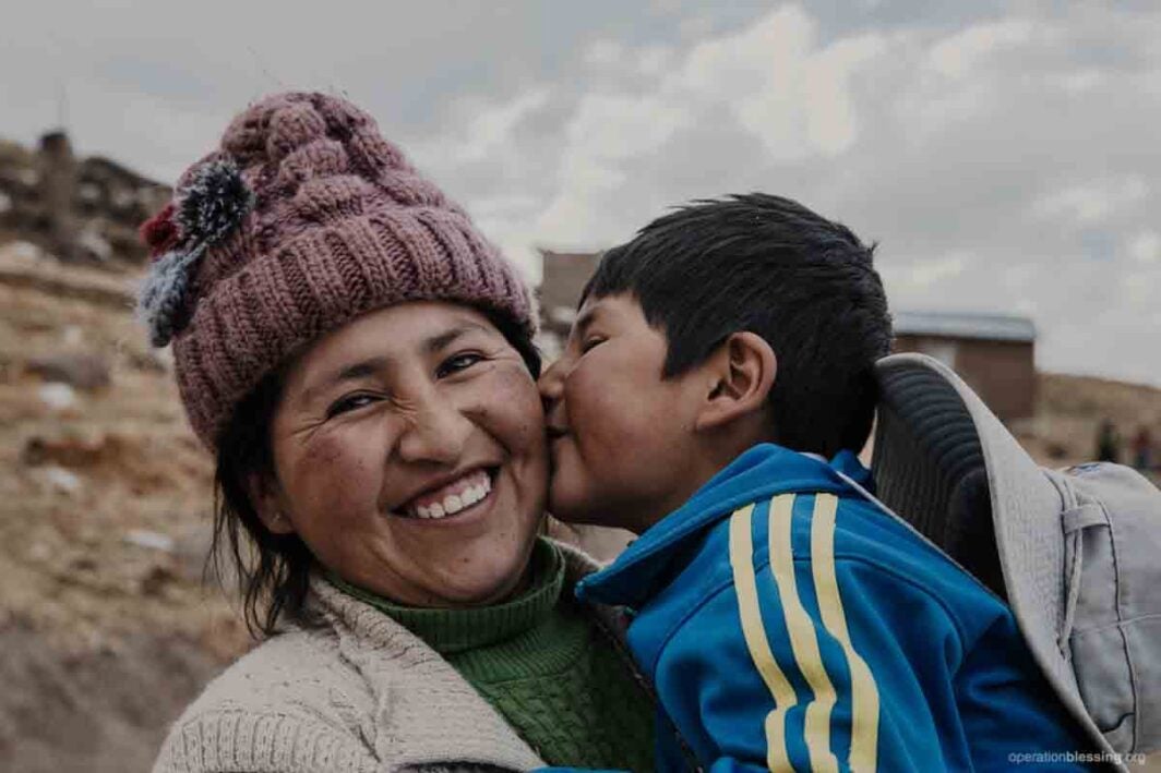 child gives mother a kiss outside medical center in peru